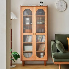 a living room with a green chair next to a wooden cabinet and clock on the wall