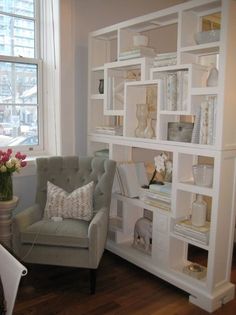 a living room filled with lots of furniture and bookshelves next to a window