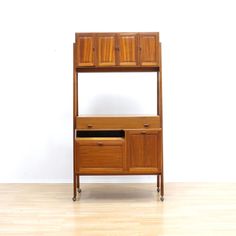 a wooden shelf with two drawers on wheels and an open drawer below it, against a white wall