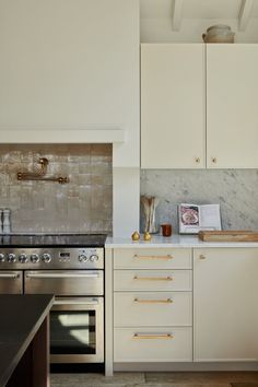 a kitchen with an oven, stove and counter tops in white painted wood paneling