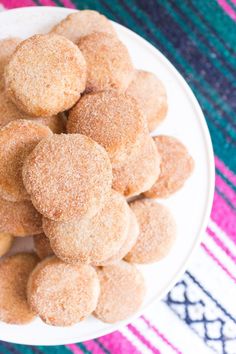 a white plate filled with sugared donuts on top of a colorful table cloth