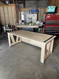 a wooden table sitting inside of a garage next to other workbench and tools