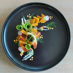 a black plate topped with food on top of a wooden table