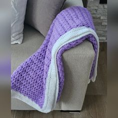 a purple and white crocheted blanket sitting on top of a couch