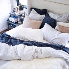 an unmade bed with several pillows and blankets on it