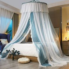 a canopy bed with white drapes and blue curtains on the top, in a bedroom