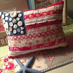 an american flag pillow with buttons on it and a starfish laying next to it