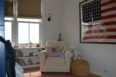 an american flag is hanging in the corner of a room with a chair and rug