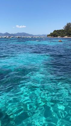 clear blue water with boats in the distance