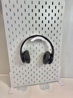 headphones are mounted on a white wall with perfored holes in the background