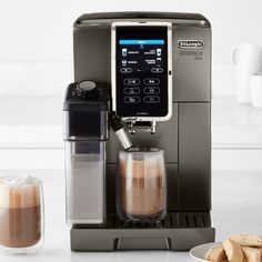 an espresso machine sitting on top of a counter next to some cookies and coffee