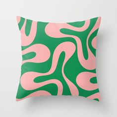 a pink and green pillow with wavy lines on the front, sitting on a white wall