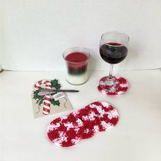 crocheted red and white coasters next to a glass of wine