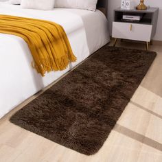 a brown rug on the floor next to a bed