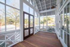 an empty porch with wooden floors and large windows