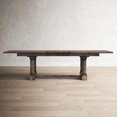 a wooden table sitting on top of a hard wood floor next to a white wall