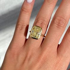 a woman's hand with a yellow diamond ring on top of her left hand