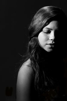 a black and white photo of a woman with her eyes closed looking down at something