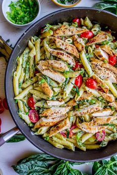 a pan filled with pasta and chicken on top of a table next to other ingredients