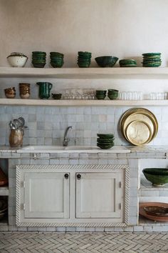 a kitchen with white cabinets and green dishes on the shelves above it is filled with plates