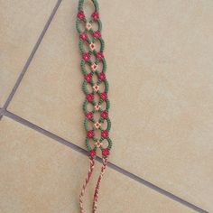 a close up of a bracelet on a tile floor with beads and chains attached to it