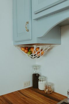 a kitchen with blue cabinets and wood counter tops is pictured in this image, there are fruit on the shelf above the sink