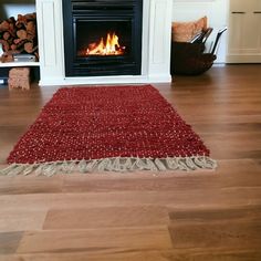 a red rug sitting on top of a hard wood floor next to a fire place