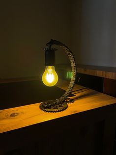 a light bulb sitting on top of a wooden table next to a wall mounted clock