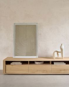 a white vase sitting on top of a wooden shelf next to a mirror and other items