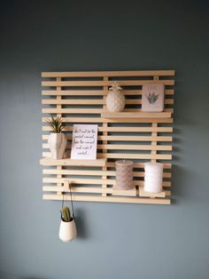 a wall mounted shelf with candles and other items on top of it in front of a blue wall