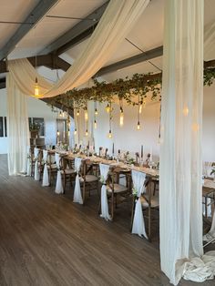 a long table is set up with white drapes and greenery on the ceiling