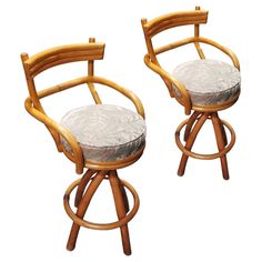 two wooden barstools with padded seats on white backrounds, one in bamboo and the other in grey fabric