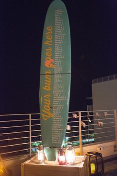 a large surfboard sitting on top of a wooden table next to a railing at night