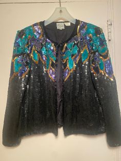 Gorgeous women's 1970's "Stenay" brand beaded jacket size small. The fully lined jacket which closes with hooks & eyes down the front can be worn open or closed! It has approx 18 hooks & eyes, small shoulder pads & is very clean inside & out!  The scoop neck is covered with black sequins with dimensional rich encrusted designs in gold, turquoise, dark purple/navy looking sequins, bugles, small beads & a large matching color bead in the floral center.  It's 100% silk outside & inside. The beading Embroidered Fitted Outerwear For Party, Fitted Embroidered Outerwear For Party, Embroidered Evening Blazer For Winter, Embroidered Winter Evening Outerwear, Vintage Blazer For Fall Party, Vintage Fall Blazer For Parties, Vintage Fall Party Blazer, Fitted Beaded Evening Outerwear, Winter Outerwear With Sequins