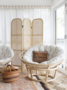 two wicker chairs and a round table in a room with sheer curtains on the windowsill