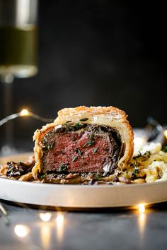 a piece of meat is sitting on a plate with some rice and wine in the background