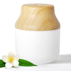 a white vase with a wooden lid next to a flower