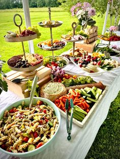 a table filled with lots of food on top of a lush green field covered in grass