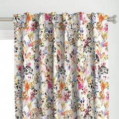 the curtains are decorated with colorful flowers and leaves on white fabric, hanging in front of a window