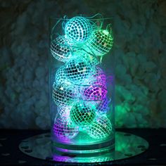 a glass filled with disco balls sitting on top of a table next to a wall