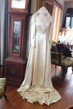 a wedding dress on display in front of a grandfather clock