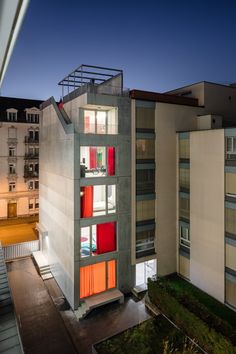 an apartment building with red and yellow shutters on the windows is lit up at night