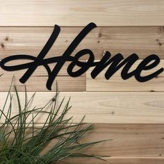 a sign that says home on the side of a wooden wall next to a potted plant