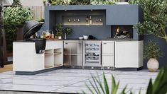 an outdoor kitchen with stainless steel appliances and potted plants