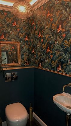 a toilet and sink in a room with wall paper on the walls, mirror above it