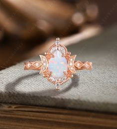 an opal and diamond ring sitting on top of a book