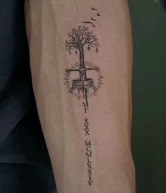 a person with a tattoo on their arm that has a cross and tree in it