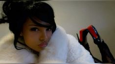 a woman with black hair wearing a white fur coat