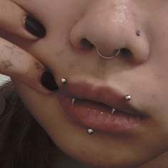 a close up of a person with piercings on her nose and nose ring in front of their face