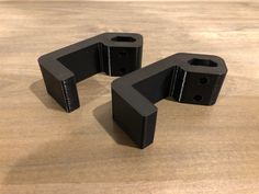 three pieces of black plastic sitting on top of a wooden table